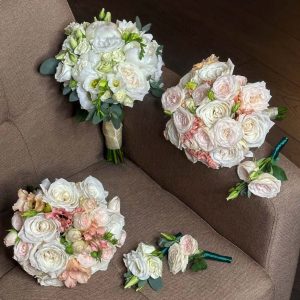 Wedding flower bouquets and boutonnieres with peonies, freesia, spray roses, lisianthus, eucalyptus, and roses