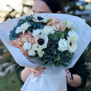 A mesmerizing bouquet named "Enchanted Garden Delight" featuring hydrangeas, anemones, gerberas, lisianthus, and dianthus in a captivating blend of colors and textures.