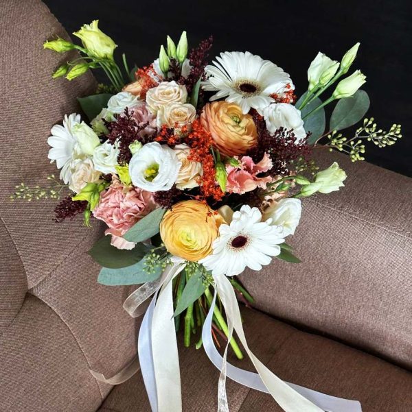 A close-up view of the Bride's Enchantment Bouquet, showcasing its beautiful roses, lilies, freesias, and lush greenery in all their bridal elegance.