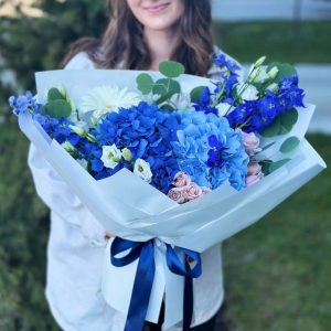 A close-up view of the "Mystical Garden Dream" bouquet, showcasing the delicate hydrangeas, lisianthus, tall delphinium spikes, vibrant gerbera daisies, spray roses, and the elegant eucalyptus leaves, creating a dreamy and enchanting arrangement.