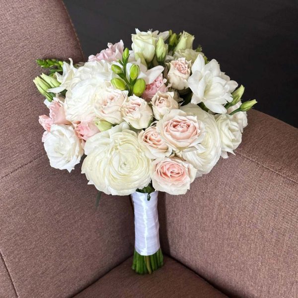 A beautifully hand-tied bridal bouquet with white roses and lilies, perfect for weddings.