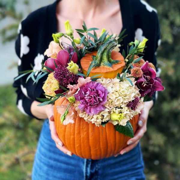 An image of the "Pumpkin Blossom Delight" bouquet, showcasing the rustic charm of a pumpkin vase filled with sunflowers, daisies, and asters, perfect for fall.