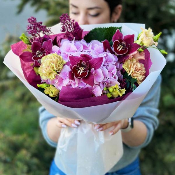 A beautiful bouquet of spring flowers featuring roses, lilies, daisies, and tulips in shades of pink, purple, and white.