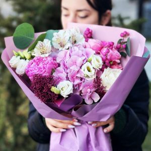 A close-up of the "Blooms of Elegance Symphony" showcasing hydrangeas, roses, peonies, eustoma, astrometry, skimmia, and eucalyptus in a harmonious and elegant floral arrangement.