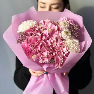 A stunning image of the "Harmony in Bloom Bouquet" showcasing a blend of hydrangeas, dianthus, chrysanthemums, and skimmia. The diverse colors and textures create a visually appealing arrangement, symbolizing love, romance, and vibrant positivity.