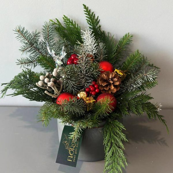Festive Table: Christmas composition with pine on the table with cones, viburnum, and red ornaments, creating an atmosphere of warmth and festive cheer.