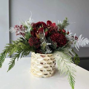 Winter Opulence: A lavish arrangement showcasing orchids, skimmia, cedar, pine, and chrysanthemums, creating an opulent and sophisticated winter floral display.