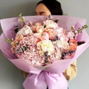 Spring Magnolia Bliss Bouquet showcasing hydrangeas, peonies, spray roses, statice, and magnolia for a delightful and enchanting display.