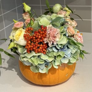 "Autumn flower arrangement featuring vibrant blooms and decorative pumpkins, perfect for fall celebrations."