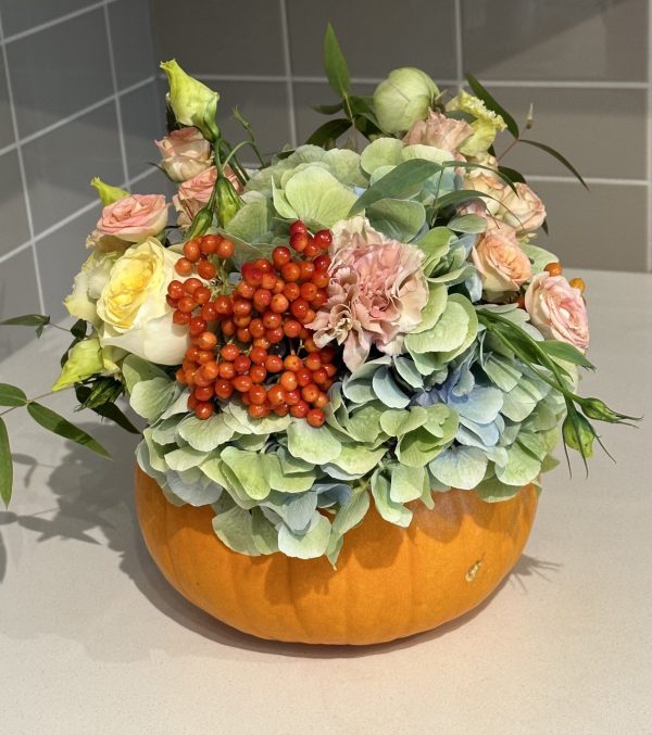 "Autumn flower arrangement featuring vibrant blooms and decorative pumpkins, perfect for fall celebrations."