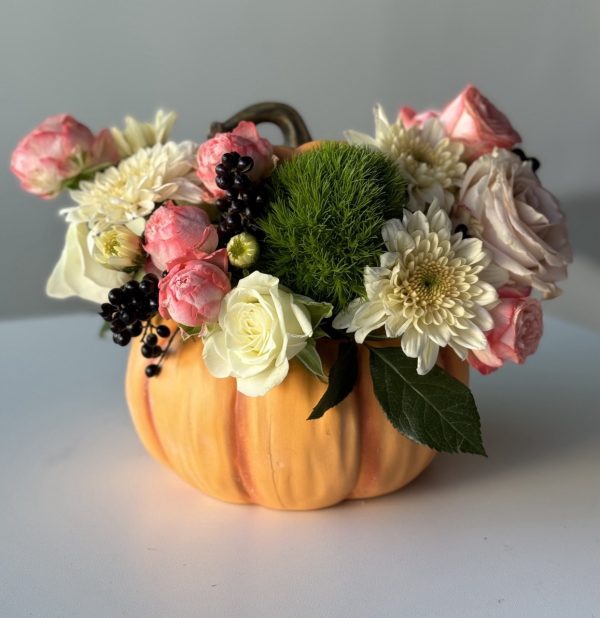 Vibrant flower arrangement featuring seasonal blooms and decorative pumpkins, perfect for autumn celebrations.