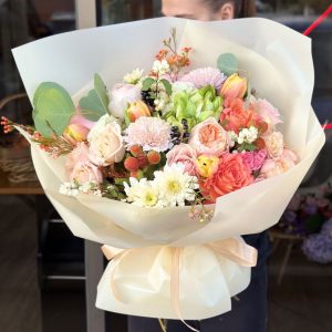 A vibrant bouquet titled "Golden Glow," featuring sunny tulips, cheerful chrysanthemums, and adorable roses, elegantly arranged and wrapped in creamy stunning packaging.