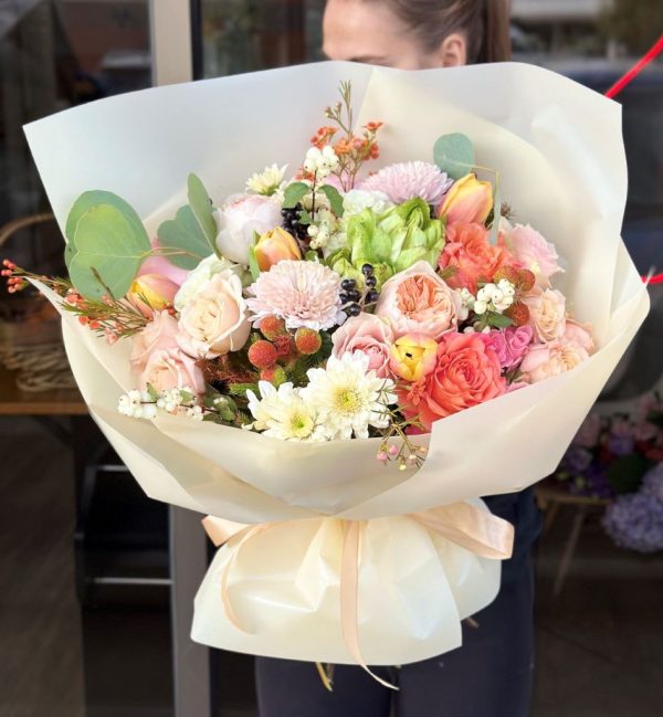 A vibrant bouquet titled "Golden Glow," featuring sunny tulips, cheerful chrysanthemums, and adorable roses, elegantly arranged and wrapped in creamy stunning packaging.