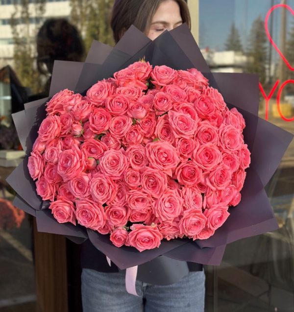 A beautifully arranged bouquet titled "Melody of Tenderness," featuring bright coral spray roses, elegantly wrapped in dark grey paper.