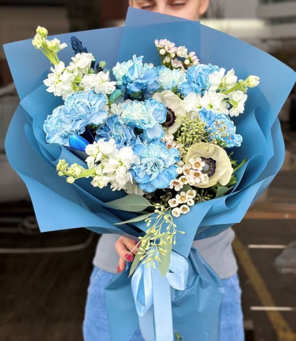 A stunning bouquet titled "Mystic Blue Charm," featuring elegant blue carnations, delicate matthiolas, and striking anemones, beautifully arranged and wrapped in eco-friendly packaging.