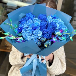 A striking bouquet titled "Sapphire Splash," featuring deep blue roses, vibrant tulips, and delicate hydrangeas, elegantly arranged and wrapped in blue paper.