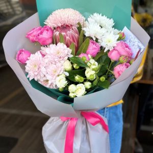 A vibrant bouquet titled "Spring Wishes," featuring cheerful chrysanthemums, lively protea, and fragrant spray roses, beautifully arranged and wrapped in grey paper.