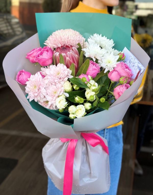 A vibrant bouquet titled "Spring Wishes," featuring cheerful chrysanthemums, lively protea, and fragrant spray roses, beautifully arranged and wrapped in grey paper.