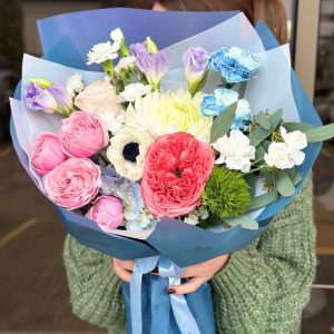 A vibrant bouquet titled "Botanical Bliss," featuring cheerful spray roses, elegant chrysanthemums, fragrant carnations, and lush greenery, elegantly arranged and wrapped in elegant blue packaging.