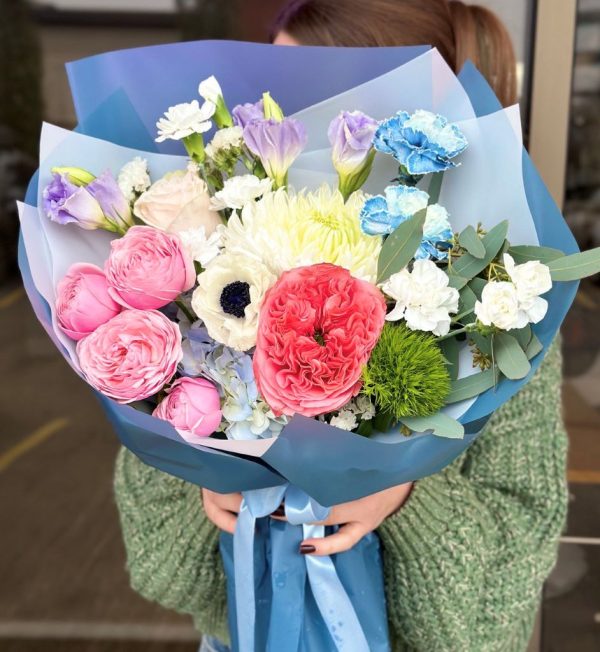 A vibrant bouquet titled "Botanical Bliss," featuring cheerful spray roses, elegant chrysanthemums, fragrant carnations, and lush greenery, elegantly arranged and wrapped in elegant blue packaging.