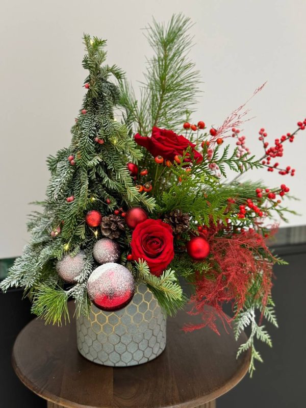 Christmas arrangement "Season's Greetings" featuring red roses, ilex berries, and lush greenery, capturing the festive spirit of the season.