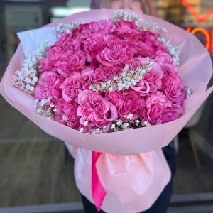 Floral arrangement "Purple Reverie" featuring deep purple roses and delicate baby's breath, creating an elegant and serene display.