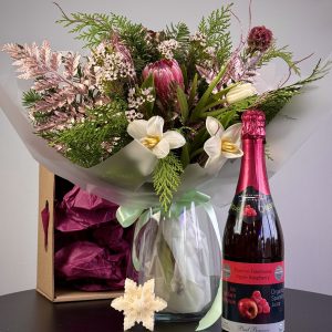 "Christmas gift set featuring seasonal flowers with a vase, a sparkling beverage, and candles, perfect for holiday celebrations."