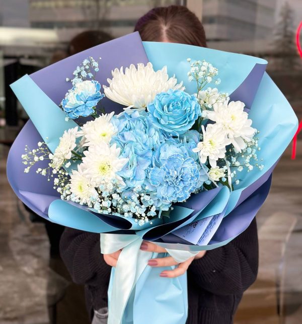 Flower arrangement with blue hydrangeas, blue roses, and white chrysanthemums, showcasing elegance and serenity.