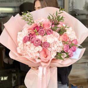 Flower arrangement with pink hydrangeas, spray roses, roses, and eucalyptus, showcasing elegance and freshness.