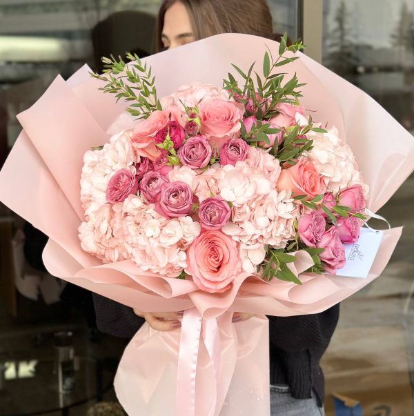 Flower arrangement with pink hydrangeas, spray roses, roses, and eucalyptus, showcasing elegance and freshness.