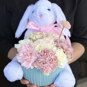 A cute rabbit toy surrounded by vibrant pink and white carnations, creating a cheerful and colorful arrangement.