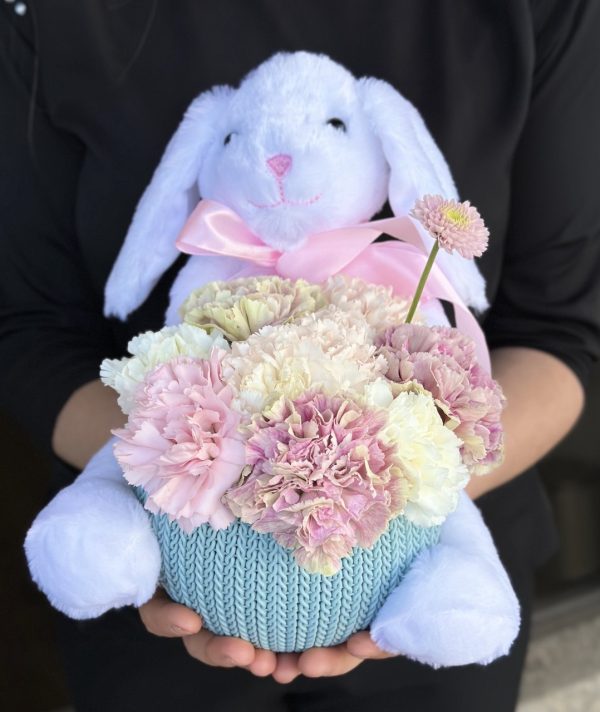 A cute rabbit toy surrounded by vibrant pink and white carnations, creating a cheerful and colorful arrangement.