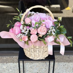 Basket arrangement of seasonal flowers in delicate pastel shades.