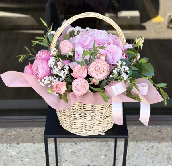 Basket arrangement of seasonal flowers in delicate pastel shades.