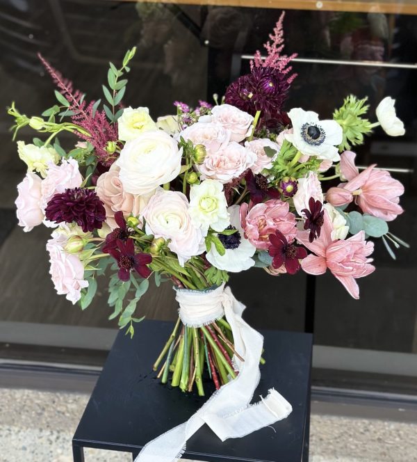 A lush blush and burgundy wedding bouquet handcrafted in Edmonton using garden roses, ranunculus, dahlias, and anemones. Ideal for romantic and modern weddings.